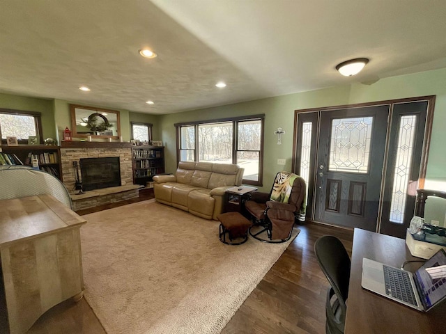 living room featuring a fireplace, dark wood-type flooring, and plenty of natural light