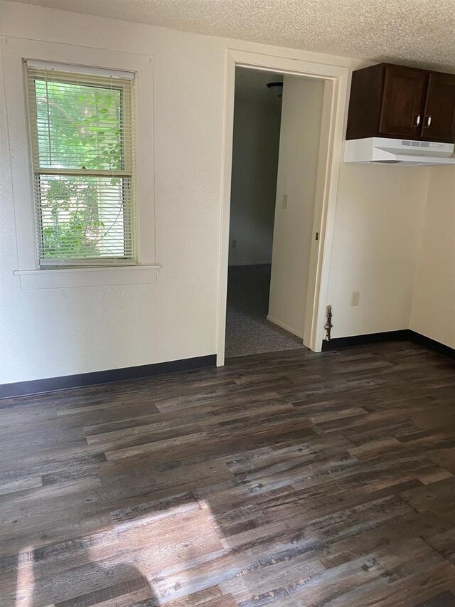 spare room featuring dark hardwood / wood-style flooring and a textured ceiling