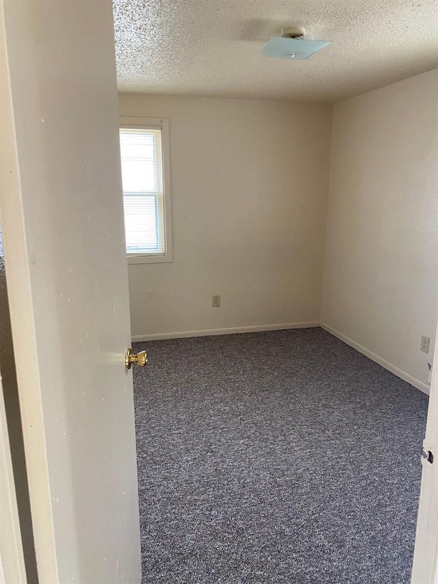 empty room with a textured ceiling and dark colored carpet