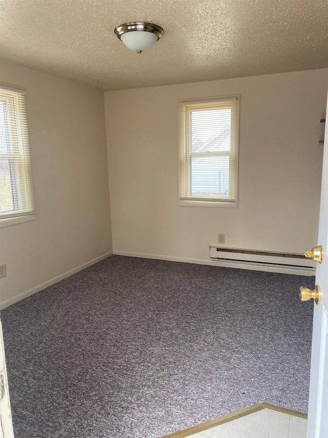 carpeted empty room with a baseboard radiator, a healthy amount of sunlight, and a textured ceiling