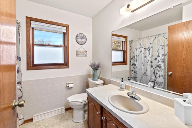 bathroom with vanity, tile walls, a baseboard radiator, and toilet