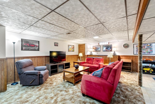 living room with a paneled ceiling and wood walls