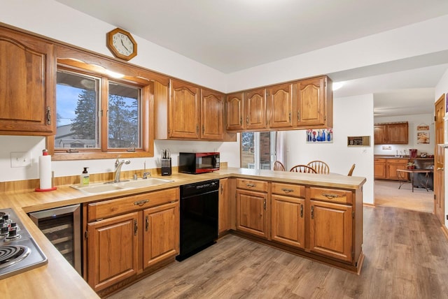 kitchen featuring dishwasher, sink, light wood-type flooring, and kitchen peninsula