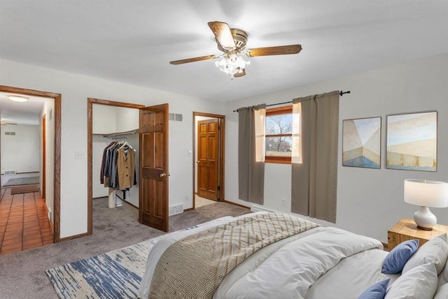 carpeted bedroom with a spacious closet, ceiling fan, and a closet