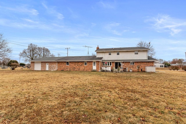 back of property featuring a garage and a yard