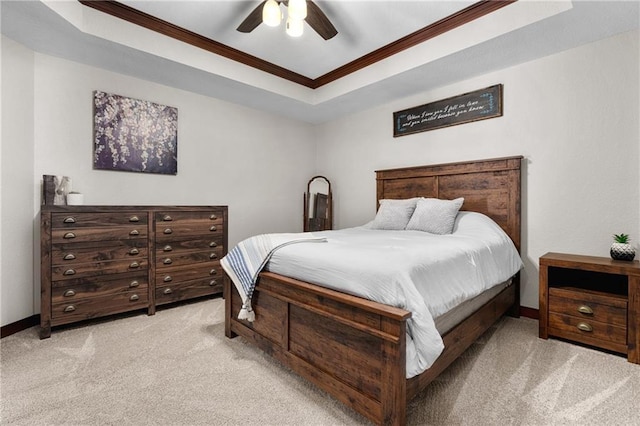 bedroom with ceiling fan, light colored carpet, ornamental molding, and a raised ceiling