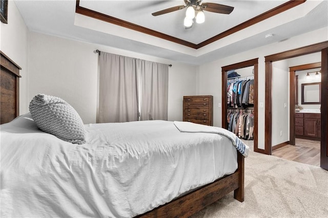 bedroom featuring a raised ceiling, crown molding, a spacious closet, and a closet