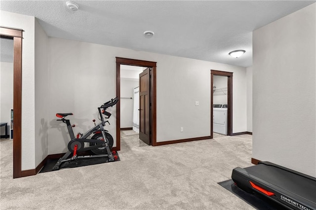 workout area featuring light colored carpet, washer / dryer, and a textured ceiling