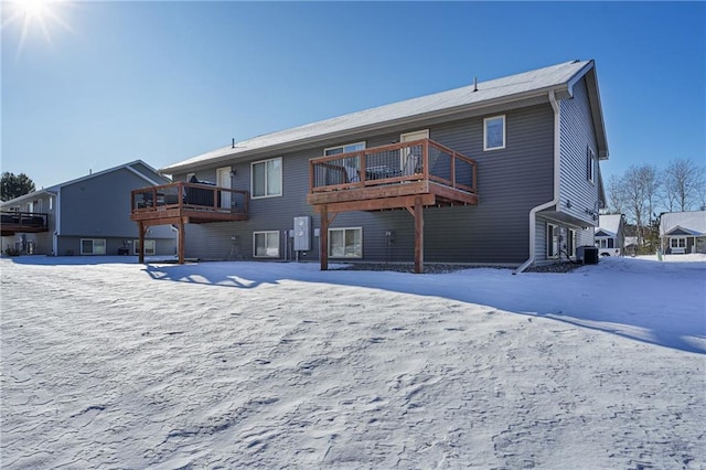 snow covered house with a deck and central AC unit