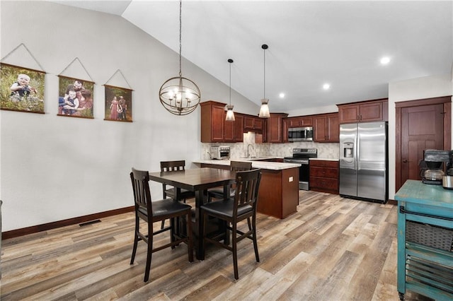 dining space featuring an inviting chandelier, sink, light hardwood / wood-style flooring, and high vaulted ceiling