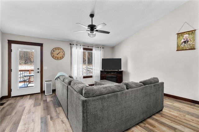 living room featuring wood-type flooring, vaulted ceiling, ceiling fan, and a textured ceiling