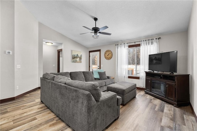 living room featuring ceiling fan, lofted ceiling, a textured ceiling, and light hardwood / wood-style flooring