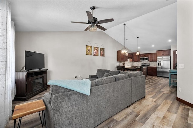 living room with lofted ceiling, hardwood / wood-style floors, and ceiling fan