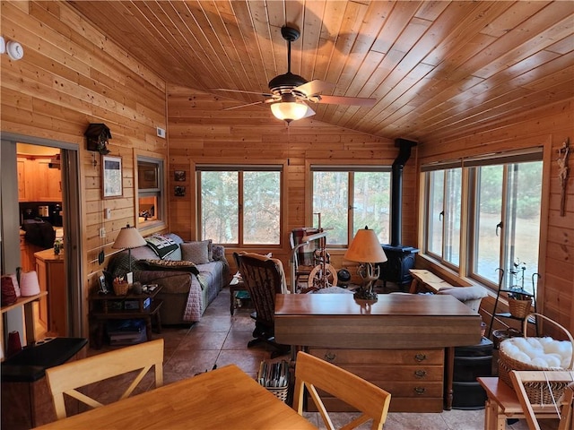 dining space with lofted ceiling, a wealth of natural light, wooden walls, and a wood stove