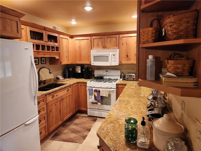 kitchen featuring sink, light stone counters, a textured ceiling, and white appliances