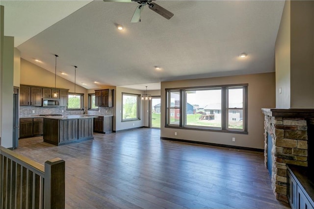 unfurnished living room featuring dark wood-type flooring, sink, a fireplace, and ceiling fan with notable chandelier