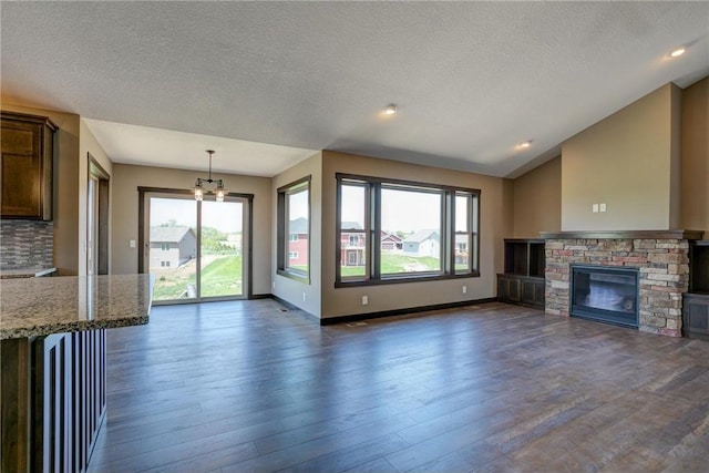 unfurnished living room with lofted ceiling, a fireplace, dark hardwood / wood-style floors, and plenty of natural light