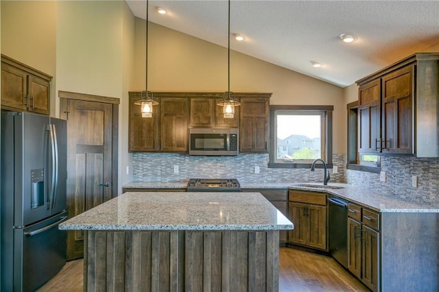 kitchen featuring pendant lighting, stainless steel appliances, a center island, and sink