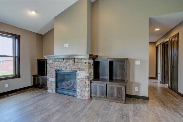 unfurnished living room with a stone fireplace and light hardwood / wood-style flooring