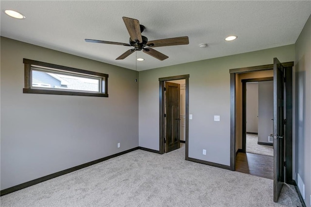 unfurnished bedroom featuring ceiling fan, light colored carpet, and a textured ceiling