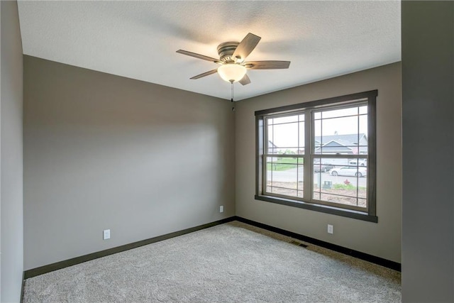 empty room featuring light carpet, a textured ceiling, and ceiling fan