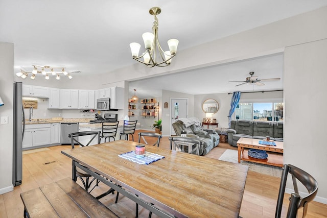 dining area with ceiling fan with notable chandelier and light wood-type flooring