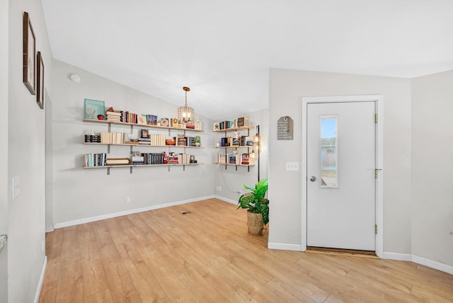 entrance foyer with lofted ceiling, a chandelier, and light wood-type flooring