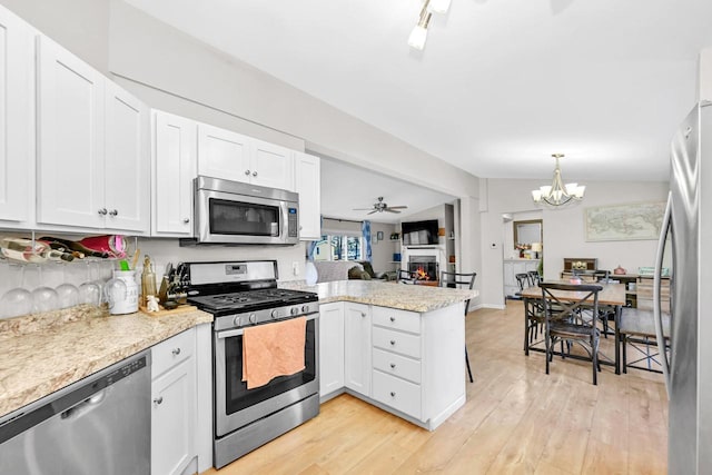 kitchen featuring light hardwood / wood-style flooring, appliances with stainless steel finishes, white cabinetry, vaulted ceiling, and kitchen peninsula