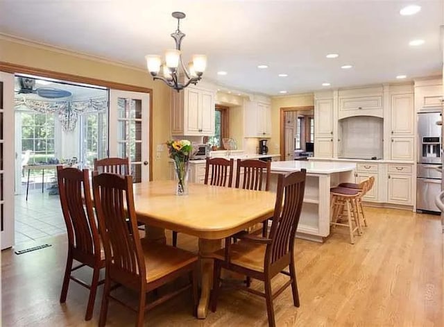 dining area featuring crown molding, light hardwood / wood-style floors, and a notable chandelier