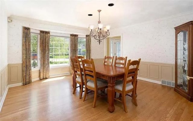 dining area with hardwood / wood-style flooring, crown molding, and a chandelier