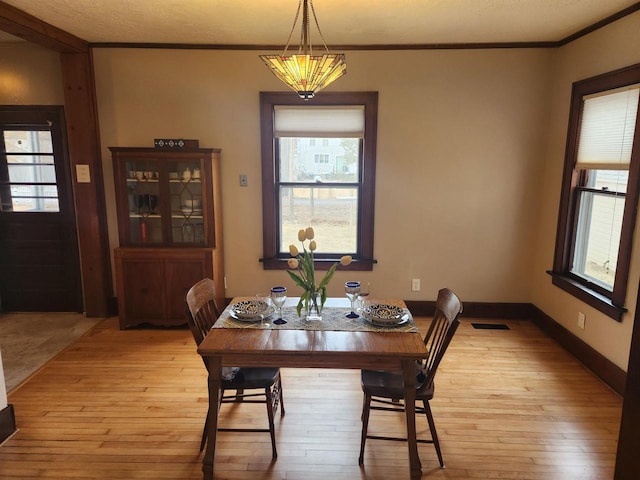 dining room with ornamental molding and light hardwood / wood-style flooring