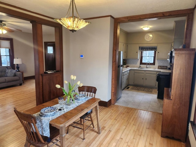 dining room with sink, light hardwood / wood-style flooring, and ornamental molding