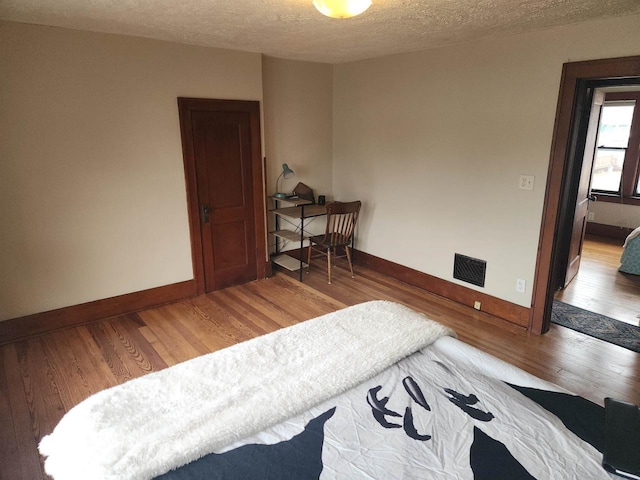 bedroom with hardwood / wood-style flooring and a textured ceiling