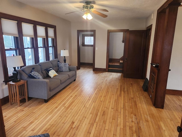 living room with ceiling fan, a textured ceiling, and light hardwood / wood-style floors