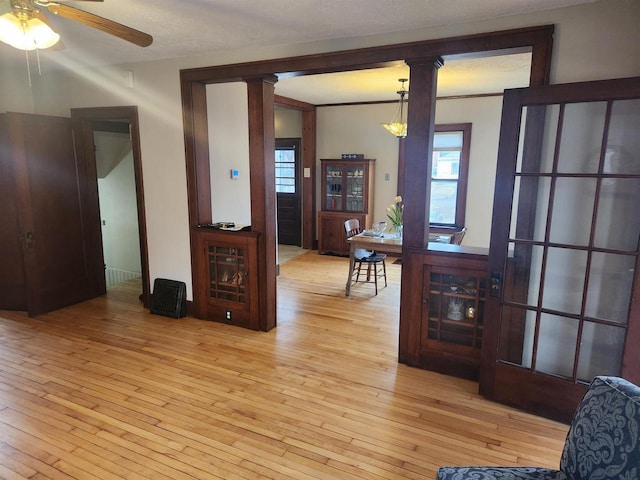 interior space with ornate columns, ceiling fan, and light wood-type flooring