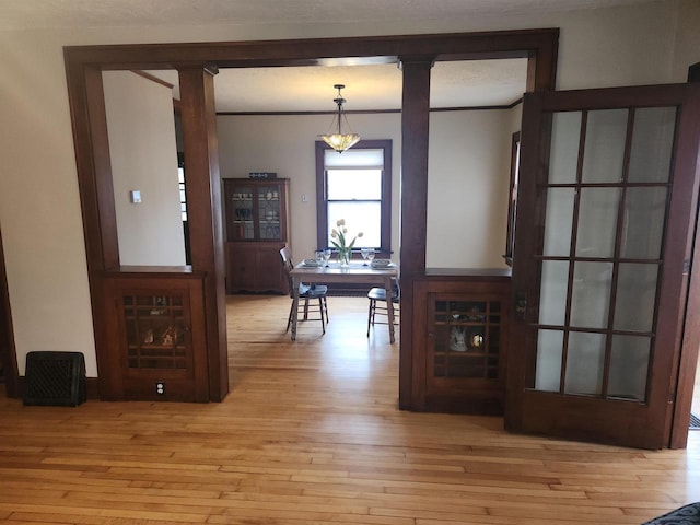 dining area with crown molding, decorative columns, and light wood-type flooring