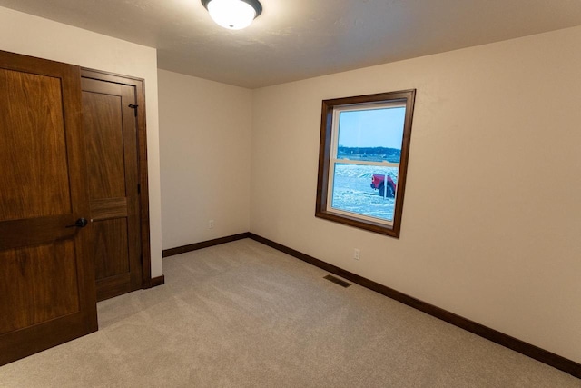 spare room featuring light colored carpet