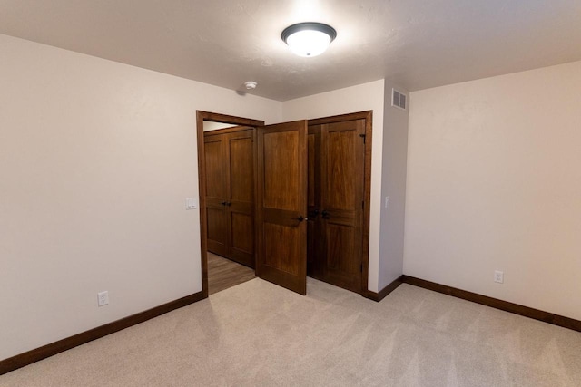 unfurnished bedroom with a closet and light carpet