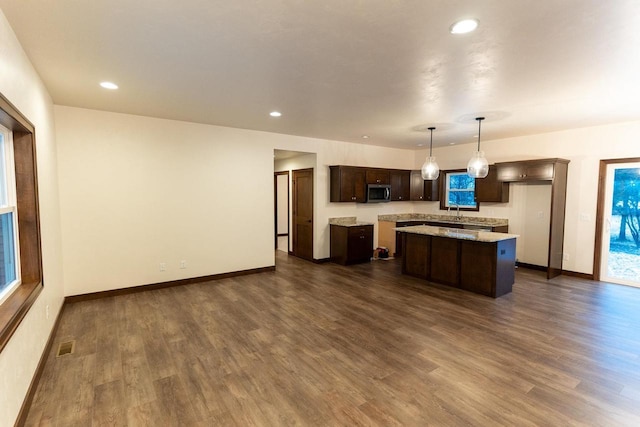 kitchen featuring dark hardwood / wood-style floors, decorative light fixtures, a center island, and dark brown cabinets