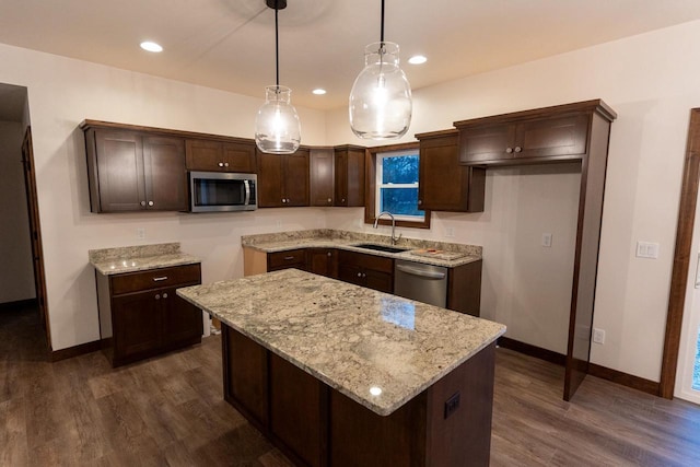 kitchen with sink, appliances with stainless steel finishes, hanging light fixtures, a center island, and dark hardwood / wood-style floors