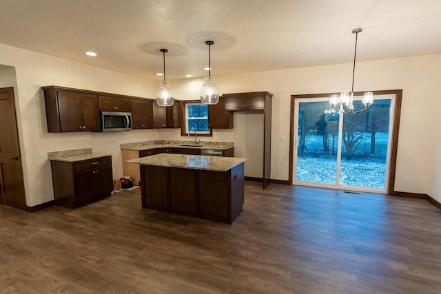 kitchen with pendant lighting, sink, light stone counters, and a center island