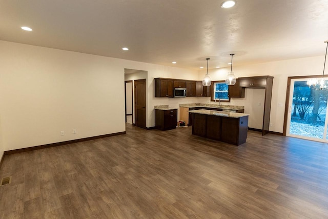 kitchen featuring pendant lighting, dark hardwood / wood-style flooring, dark brown cabinetry, and a kitchen island