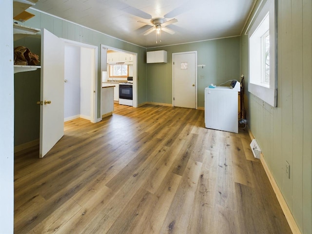 interior space featuring wood-type flooring, washer / dryer, wooden walls, and ceiling fan