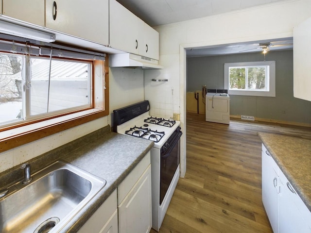 kitchen featuring white cabinetry, separate washer and dryer, sink, and white range with gas stovetop