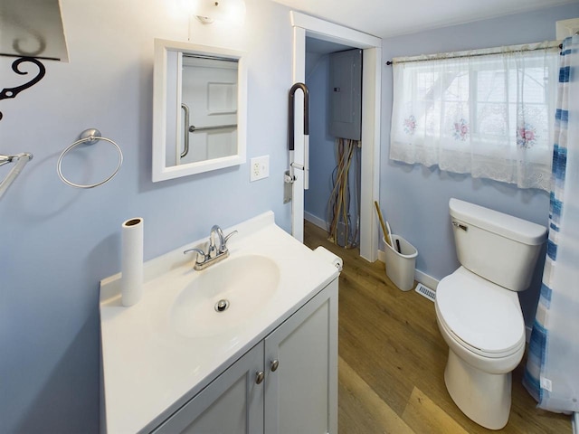 bathroom featuring vanity, wood-type flooring, electric panel, and toilet