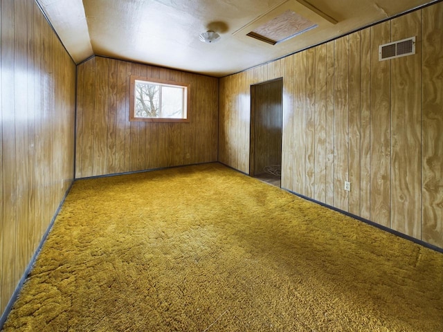 spare room with lofted ceiling, carpet floors, and wood walls