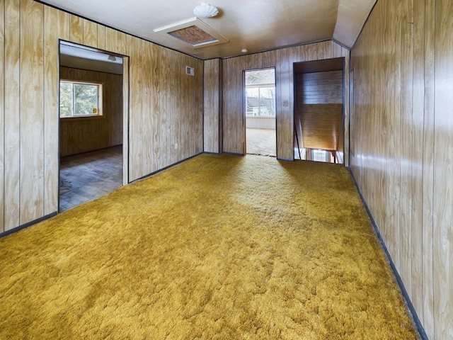 unfurnished room with wood walls and dark colored carpet