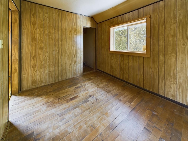 empty room with lofted ceiling, dark hardwood / wood-style flooring, and wood walls