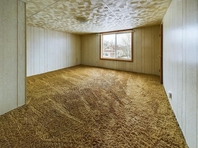 carpeted empty room with wood walls