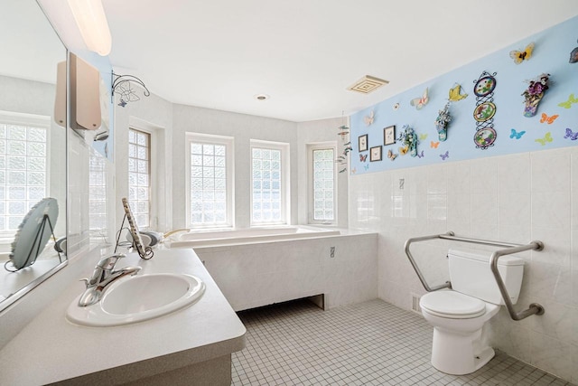 bathroom with tile patterned flooring, a healthy amount of sunlight, tile walls, and toilet